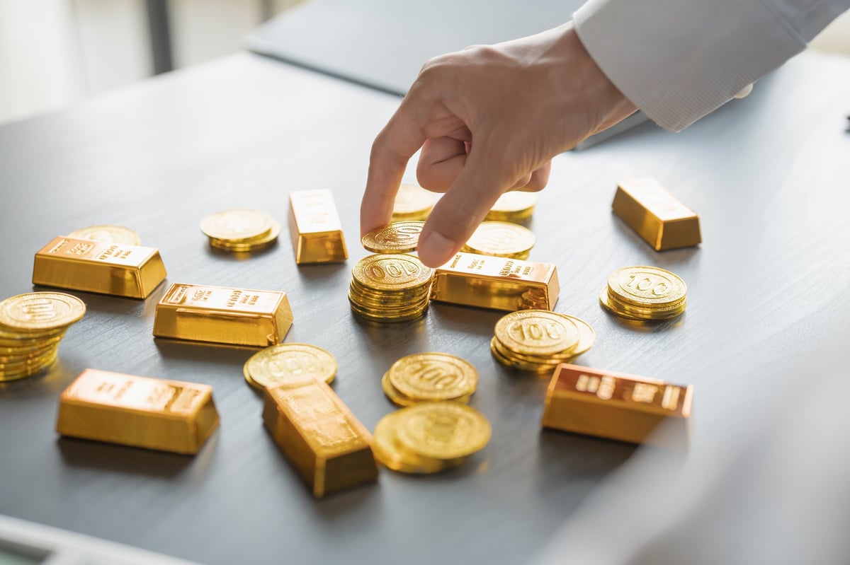 A hand offering a gold coin, representing buying and selling gold